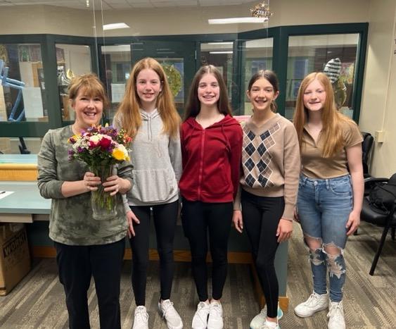 Mrs. Elliott (far left) receives flowers from 8th-graders Sarah Ley, Irelyn O'Reilly, Felicity Larson, and Mackenzie Cox