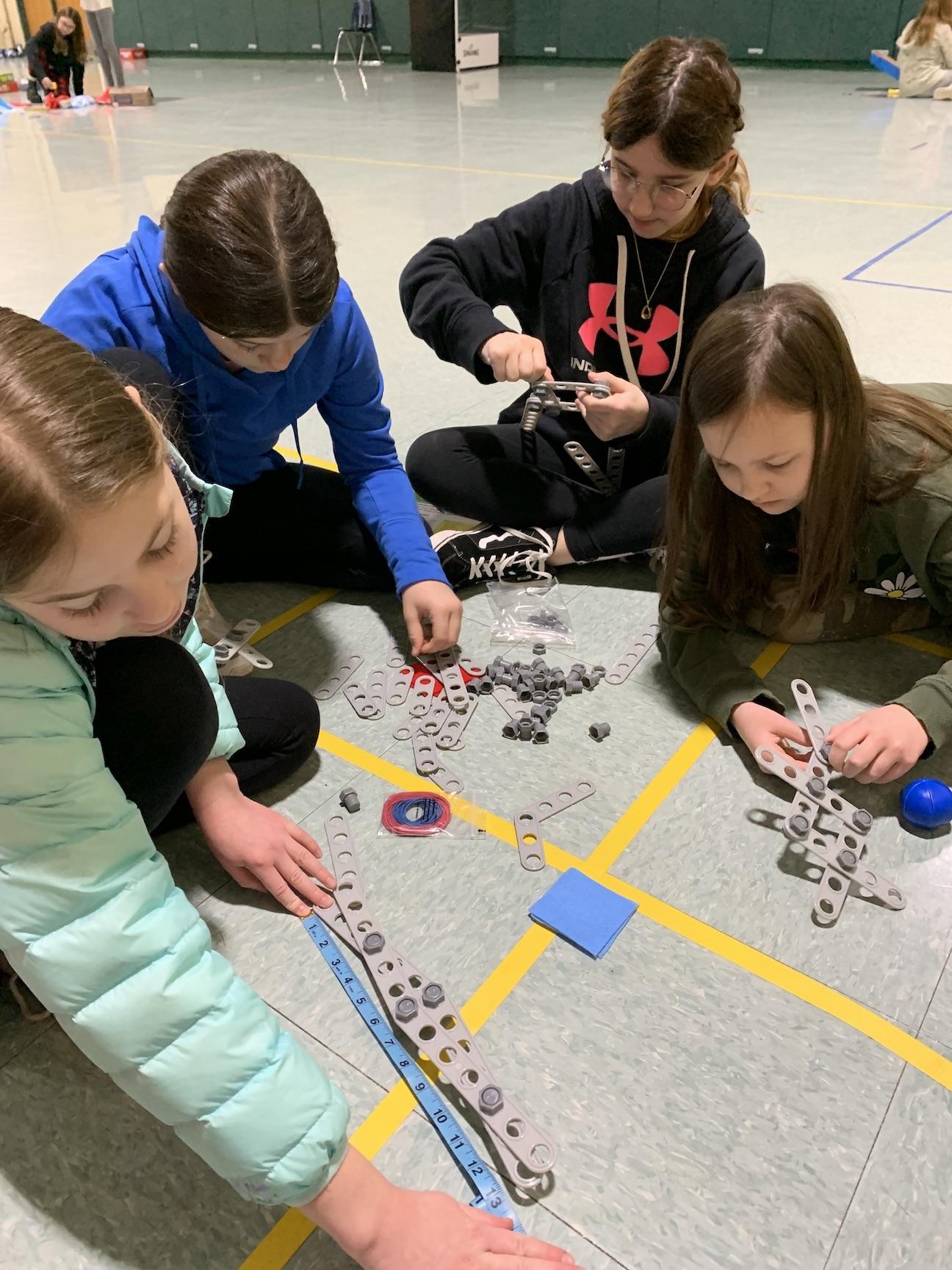 4th-graders Kiley Burnett, Talia Pecora, Gracie Beers, and Emily Ross work together to measure and build a robot arm