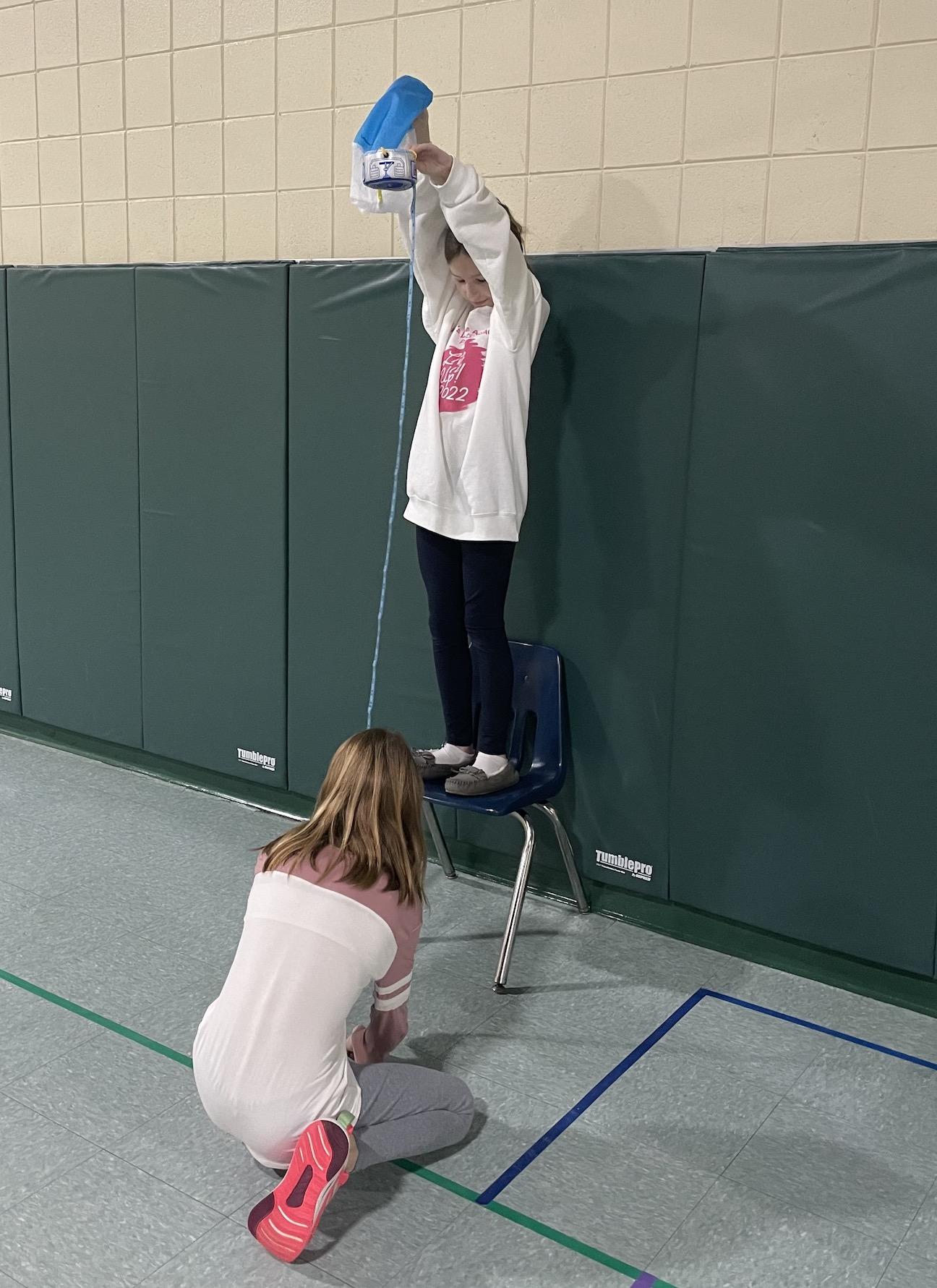 5th-graders Nia DiBernardo and Laney Rosenberry build a parachute that will allow items inside the basket to land slowly and gently