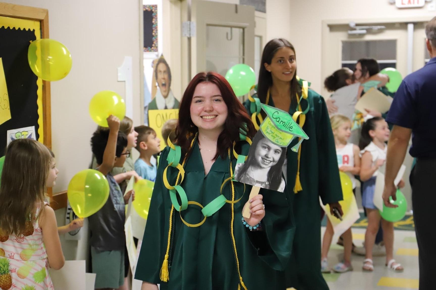 Camille Petrulak and Lillian Palladino parade through McCullough Elementary, which presented each of its seniors with a paper necklace to mark the occasion