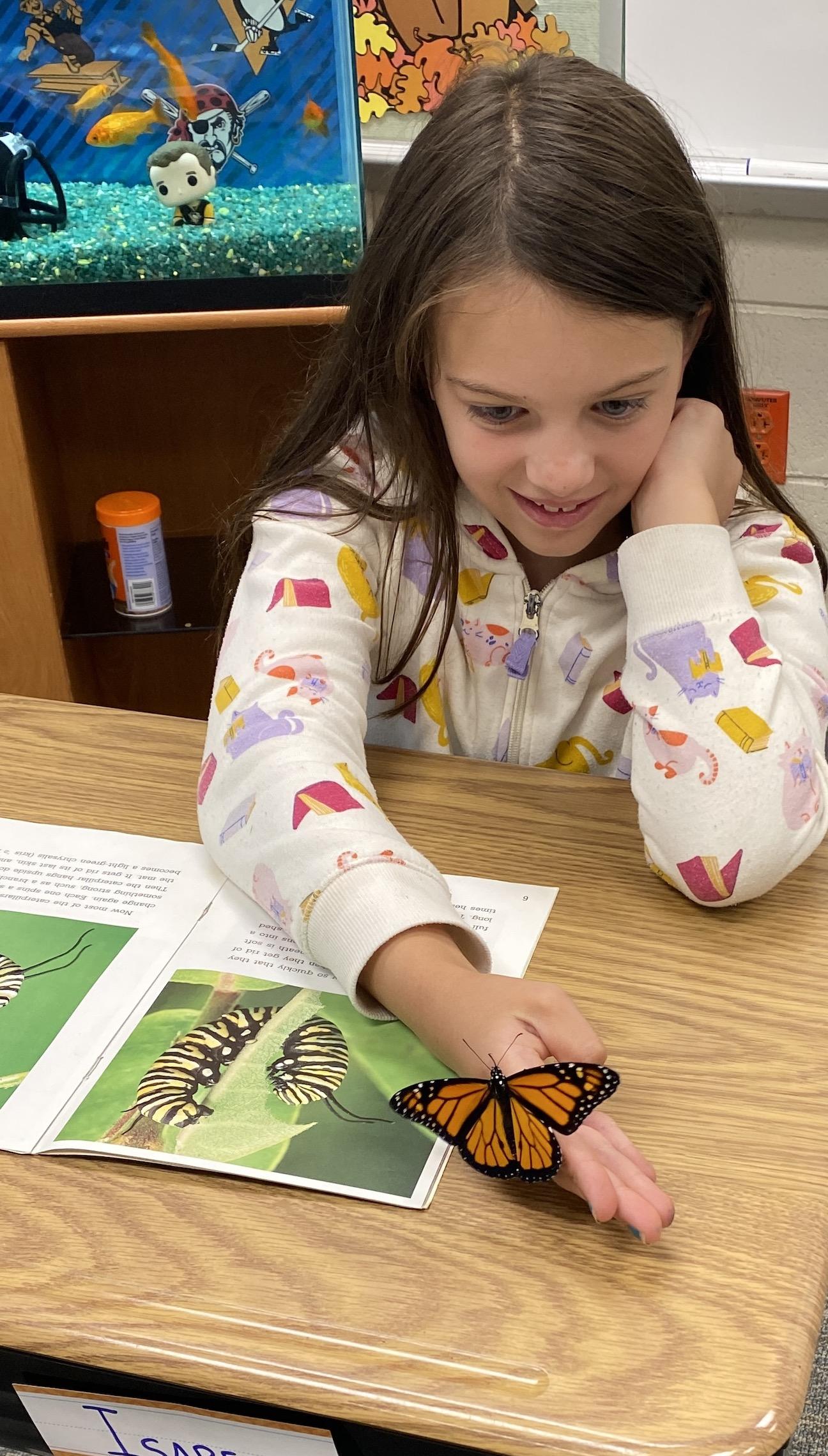 Bella Dorosh observes a butterfly while reading “The Amazing Monarch”